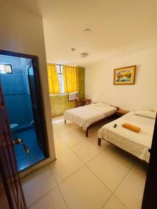 伊基托斯Amazon Green Hotel的酒店客房设有两张床和淋浴。