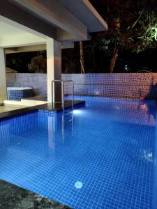 巴加C V Inn的夜间游泳池,上面有蓝色的瓷砖
