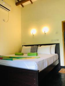 锡吉里亚Sigiri Liya Rest的墙上有两盏灯的房间的一张床位