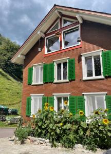 塞沃伦Old Farmhouse Loft near Vaduz的一座带绿色白色窗户和鲜花的房子