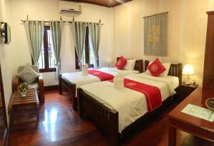 琅勃拉邦Luang Prabang Pangkham Lodge的一间卧室配有两张红色和白色床单