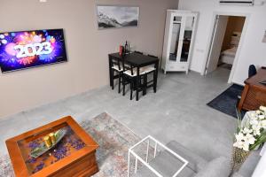 海法Deluxe Basement Apartment Bahai's Garden的客厅配有桌子和墙上的电视