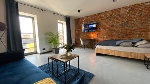 格利维采Apartamenty Gliwice Staromiejska 65的一间卧室设有砖墙、一张床和一张沙发