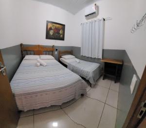 诺布里斯Casa Flor do Ipê Homes的一间卧室设有两张床、一张桌子和一个窗口