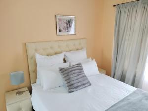 比勒陀利亚Sunrise Guesthouse的卧室配有白色的床铺和白色的枕头