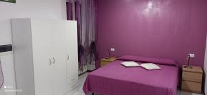 BregnanoAppartamento tra Como e Milano的紫色卧室配有一张床和两条毛巾