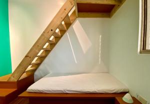 马公澎湖北吉光背包客民宿 Bayhouse Hostel Penghu的一个小房间的一个床位,设有楼梯