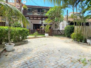 布希奥斯Praia dos Ossos Guest House - Búzios com pé na areia的一座砖砌的庭院,里面种着树木,还有一座建筑