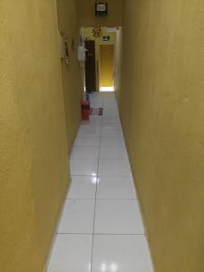 福塔莱萨Pousada Aconchego de Mãe的走廊上设有白色瓷砖地板和黄色墙壁