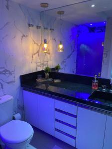 萨尔瓦多Belo apartamento Ondina Apart的浴室设有卫生间和带紫色照明的盥洗盆。