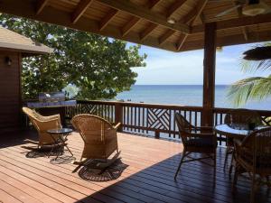 桑迪湾Reef Beach House - 2 Bedrooms and studio的一个带桌椅的木制甲板和大海