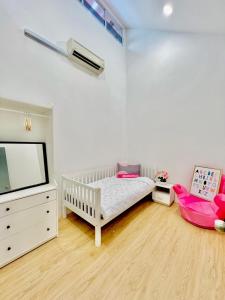 峇株巴辖The Palace Guest House, Seri Gading Batu Pahat的一间婴儿房,配有婴儿床、电视和床