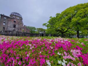 广岛Hiroshima no Yado Aioi的一座建筑前方一片粉红色的花