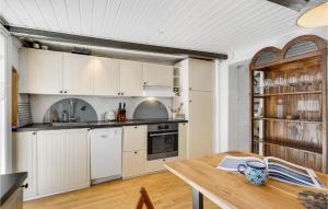 斯文堡Nice Home In Svendborg With Wifi的厨房配有白色橱柜和木桌
