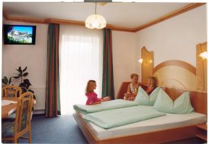 UnterlammPension Drei-Mäderl-Haus的三个女孩坐在旅馆房间的床边