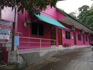 芭东海滩Baan Nakarin Guest House บ้านนครินทร์的粉红色的建筑,前面有标志