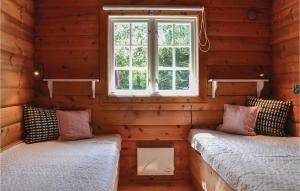 BakkegårdeNice Home In Jgerspris With Wifi的小木屋内的两张床,设有窗户