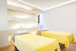 多哈Qabila Westbay Hotel by Marriott的配有黄色床单的客房内的两张床