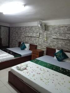金边White River guesthouse的一间卧室设有两张床和砖墙