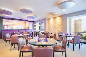 多哈Qabila Westbay Hotel by Marriott的餐厅设有桌椅和大窗户。