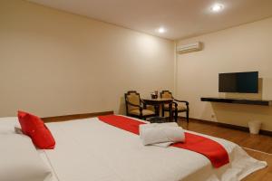 雅加达RedDoorz Plus near Dunia Fantasi Ancol的一间卧室配有一张床和一张桌子及一台电视