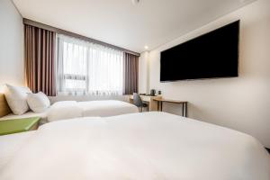 首尔Jamsil Stay Hotel的配有一张床和一台平面电视的酒店客房