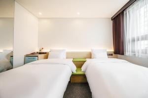 首尔Jamsil Stay Hotel的白色墙壁客房的两张床
