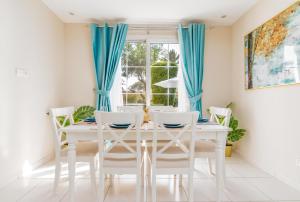迪拜Lux BnB Springs Villa Private Garden的白色的用餐室配有蓝色窗帘和白色的桌椅