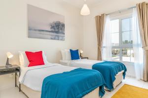 迪拜Lux BnB Springs Villa Private Garden的卧室内的两张床,配有蓝色和红色枕头
