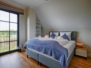 德兰斯克Reetland am Meer - Premium Reetdachvilla mit 3 Schlafzimmern, Sauna, Kamin und Massagesessel F05的大卧室配有一张带蓝色床单的大床