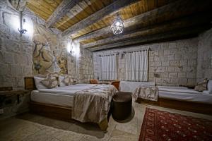 格雷梅Risus Cave Suites的石头建筑中一间带两张床的卧室