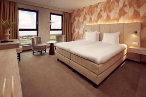 霍林赫姆Van der Valk Hotel Gorinchem的酒店客房设有一张大床和一张书桌。