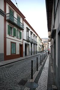 丰沙尔29 Madeira Hostel的城市中一条鹅卵石街道,有建筑