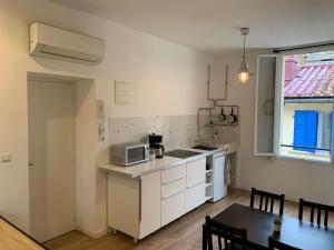 马赛Marseille LOFT 50m2 au cœur du Cours Julien的厨房配有白色橱柜、桌子和微波炉