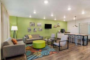 杰克逊维尔WoodSpring Suites Jacksonville - South的客厅配有沙发、椅子和桌子