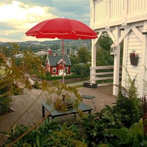 特隆赫姆Adorable 1-bedroom apartment with a fantastic view - Free Parking的露台上的红色遮阳伞,配有桌椅