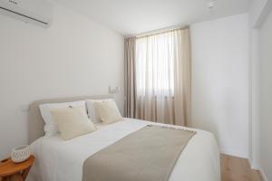 波瓦-迪瓦尔津Lapa 84 - seafront house的白色的卧室设有白色的床和窗户。