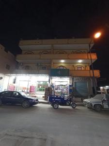 锡瓦Al-Manara Hostel Siwa Oasis的夜间停在大楼前的汽车