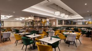 克劳利伦敦盖特威克（沃斯）假日酒店的用餐室配有桌子和黄色椅子