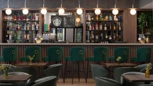 克劳利伦敦盖特威克（沃斯）假日酒店的一间设有绿色椅子的餐厅和一间酒吧