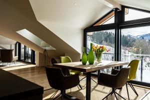 上施陶芬Alpenloft Ausblick的一间带桌椅和大窗户的用餐室