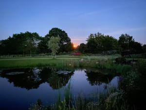 VragenderAchterhoeks Goed, Minicamping in Vragender的公园里的池塘,背面是日落