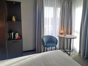 霍斯特霍斯特 - 芬洛公园酒店的一间卧室配有一张床、一张桌子和一把蓝椅
