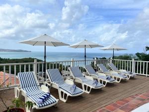 Bois dʼOrangeStunning 4-Bed Villa in Gros Islet St Lucia的甲板上的一排椅子和遮阳伞