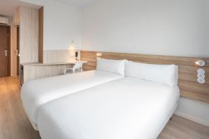 奥埃拉斯B&B HOTEL Lisboa Oeiras的一张大白色的床,位于酒店客房内