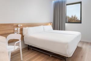 奥埃拉斯B&B HOTEL Lisboa Oeiras的卧室配有白色的床和椅子