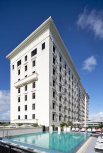 迈阿密THesis Hotel Miami的一座白色的大建筑,前面设有一个游泳池