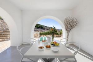 帕罗斯岛Thea Villas Paros, Villa Turquoise, private pool的白色的用餐室配有白色的桌椅