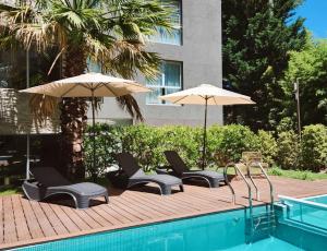 卡里罗Suite House Carilo的游泳池旁的甲板上配有椅子和遮阳伞