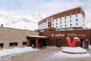 布勒伊-切尔维尼亚Valtur Cristallo Ski Resort, Dependance Cristallino的酒店大楼的背景是一座白雪覆盖的山